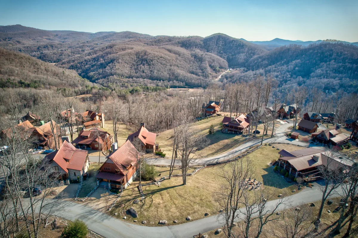 This image presents a cluster of charming cabins with red roofs nestled among surrounding mountains and open fields. The scene includes winding roads that invite exploration, and the expansive landscape instantly communicates a sense of freedom and adventure. The tranquil setting is ideal for family gatherings, outdoor picnics, and nature walks, matching the section's emphasis on outdoor fun and community amenities.