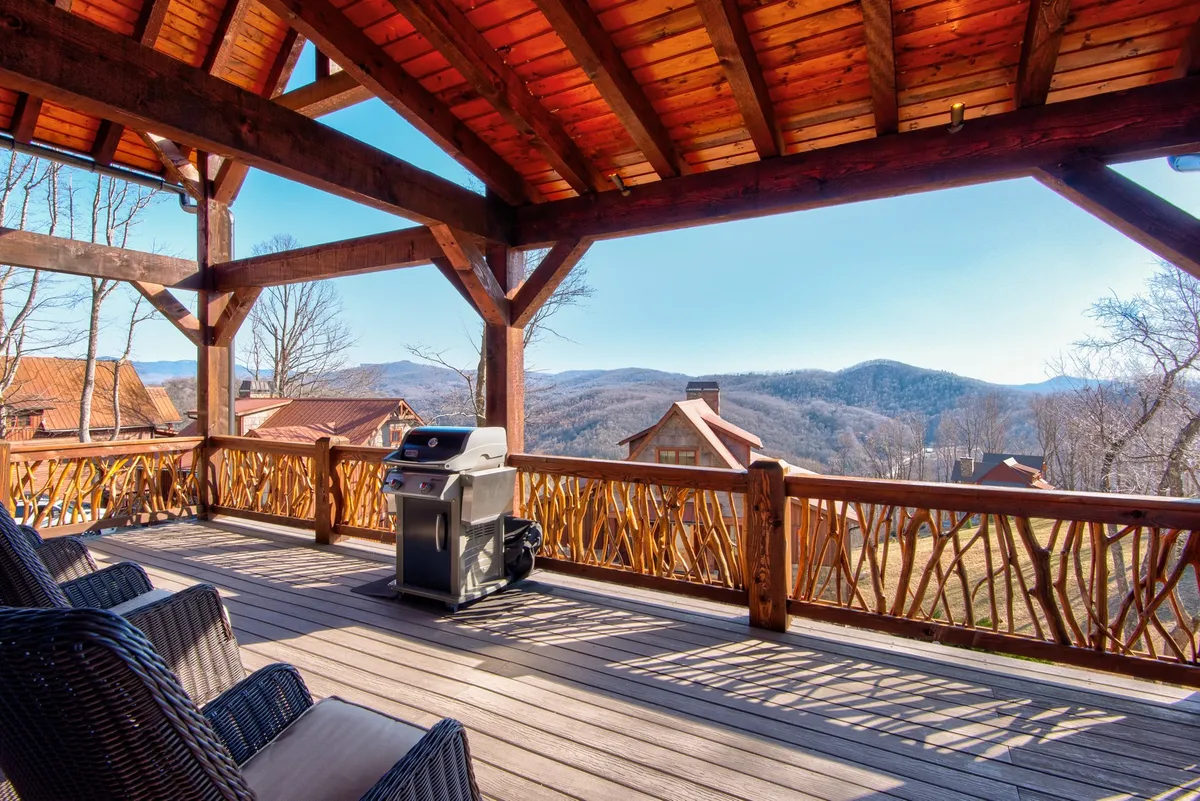 This image depicts a welcoming outdoor seating area with a grill, a wooden railing, and a stunning mountain view in the background. The setting suggests the perfect spot for barbecuing, social gatherings, or simply relaxing and taking in the natural beauty.