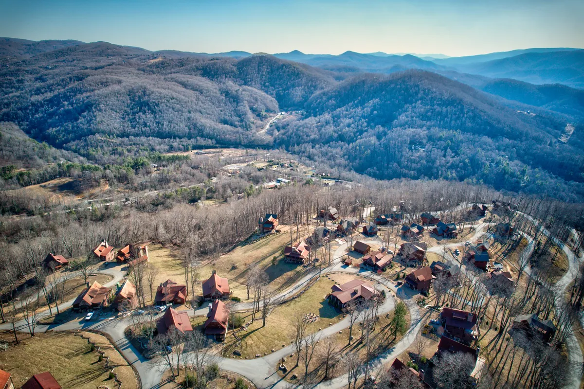 A wide view of the Eagles Nest community, featuring log cabins nestled among a mountainous landscape and winding roads. This image conveys the expansiveness and natural allure of the area, ideal for outdoor activities such as hiking and exploring.